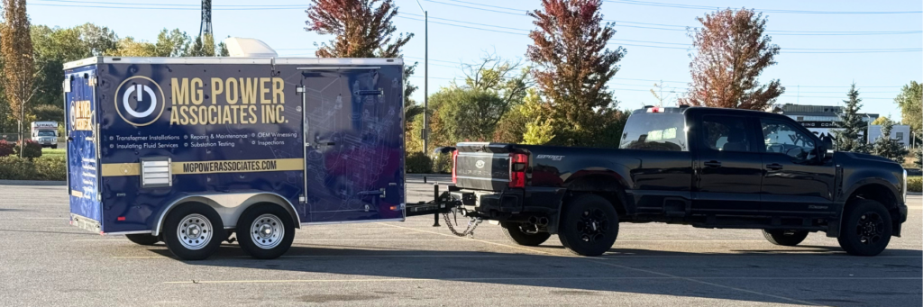 Blue MG Power Associates trailer hitched to a black pickup in a parking lot, showcasing company branding and services on the side panel.